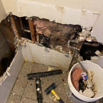 Wall opened up to expose and repair a burst pipe behind drywall during an emergency plumbing call